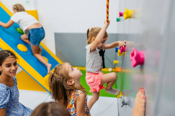 Group of girls climbing on a climbing wall in kid's playroom.
